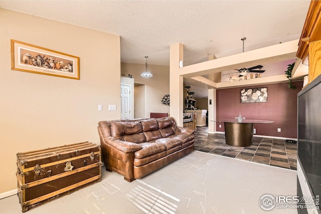 living area with vaulted ceiling, a ceiling fan, and a textured ceiling