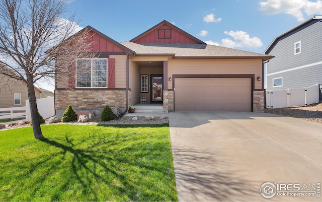 craftsman inspired home with stone siding, board and batten siding, an attached garage, fence, and a front yard