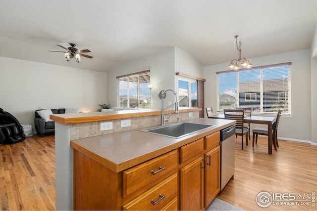 kitchen featuring light wood finished floors, a kitchen island with sink, stainless steel dishwasher, and a sink