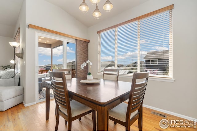 dining space featuring lofted ceiling, light wood finished floors, visible vents, baseboards, and a notable chandelier