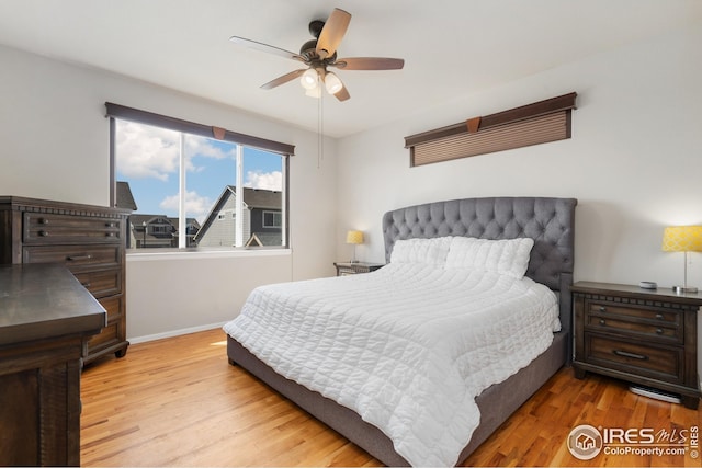 bedroom with ceiling fan, baseboards, and light wood finished floors