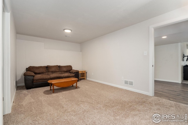 carpeted living area featuring baseboards, visible vents, and recessed lighting