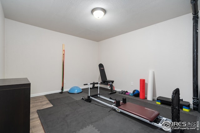 exercise room with baseboards, wood finished floors, and a textured ceiling