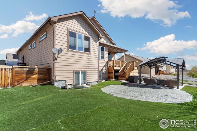 rear view of property featuring a gazebo, a patio area, a lawn, a fenced backyard, and stairs