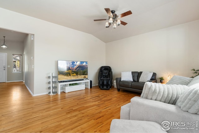 living room featuring vaulted ceiling, a ceiling fan, light wood-style floors, and baseboards