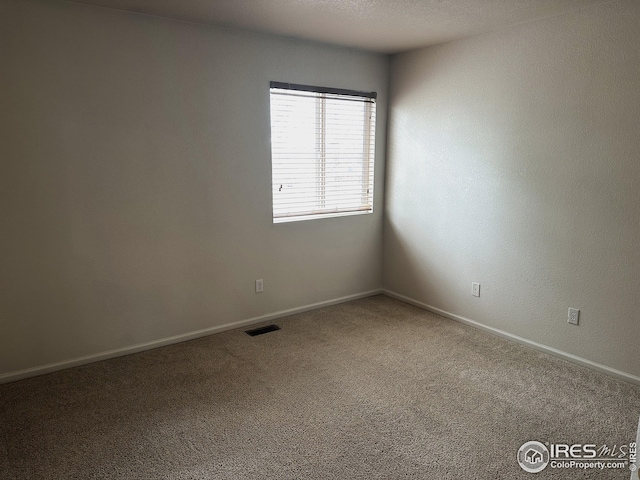 carpeted spare room with visible vents and baseboards