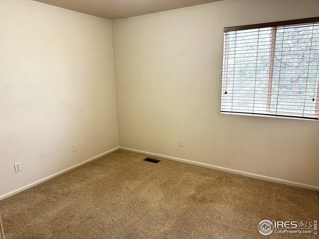carpeted empty room featuring visible vents and baseboards