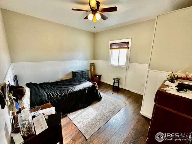 506 E 1st Ave, Otis, CO 80743 - bedroom with ceiling fan, a wainscoted wall, and dark wood-style flooring