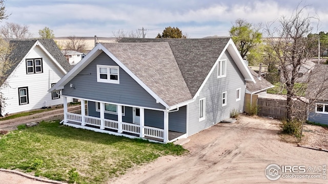 506 E 1st Ave, Otis, CO 80743 - rear view of house featuring roof with shingles, covered porch, fence, a lawn, and dirt driveway