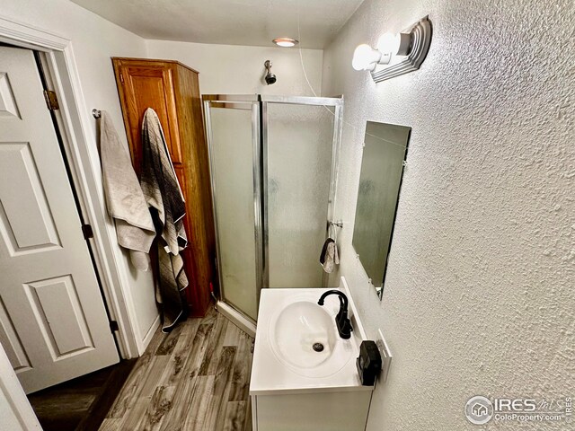 506 E 1st Ave, Otis, CO 80743 - full bath featuring wood finished floors, vanity, a stall shower, and a textured wall