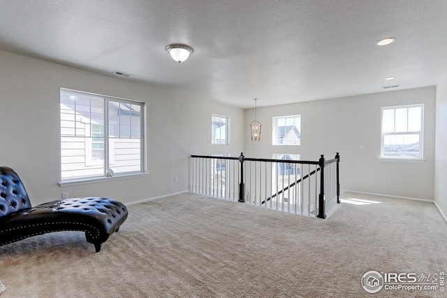 living area with baseboards, an upstairs landing, visible vents, and carpet