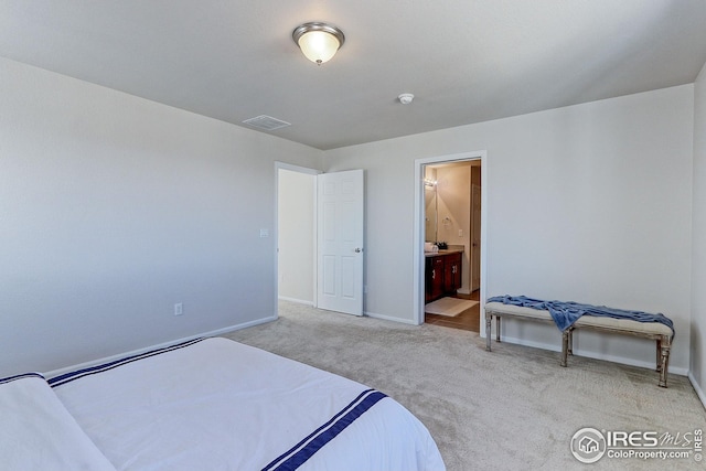 bedroom featuring baseboards, visible vents, light colored carpet, and ensuite bathroom