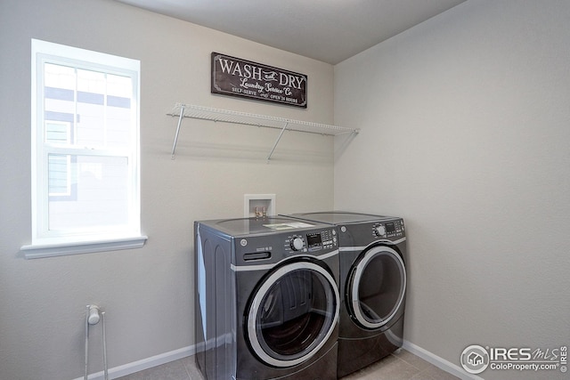 laundry area featuring light tile patterned floors, washing machine and clothes dryer, baseboards, and laundry area