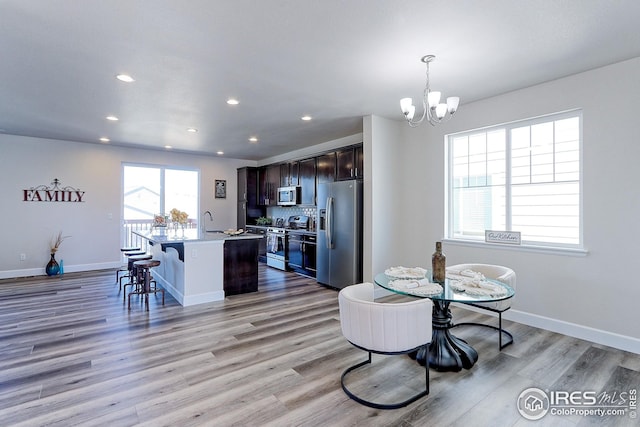dining space with baseboards, an inviting chandelier, light wood-style floors, and recessed lighting