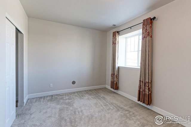 empty room featuring carpet, visible vents, and baseboards
