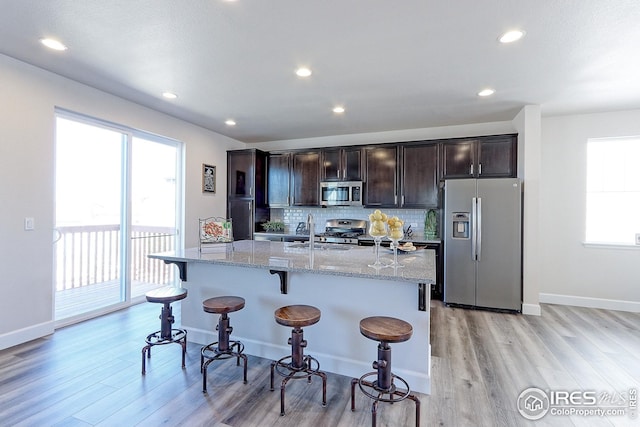 kitchen featuring light wood-type flooring, stainless steel appliances, a kitchen breakfast bar, and a sink