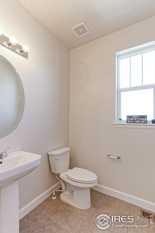 bathroom with a sink, toilet, baseboards, visible vents, and tile patterned flooring