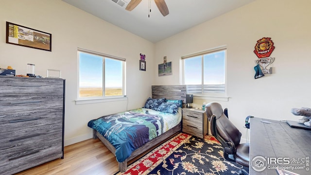 bedroom featuring baseboards, wood finished floors, ceiling fan, and multiple windows