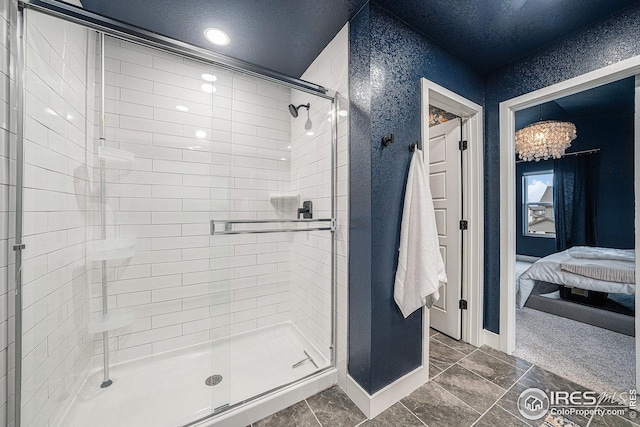 ensuite bathroom featuring a shower stall, a textured ceiling, ensuite bath, baseboards, and a notable chandelier