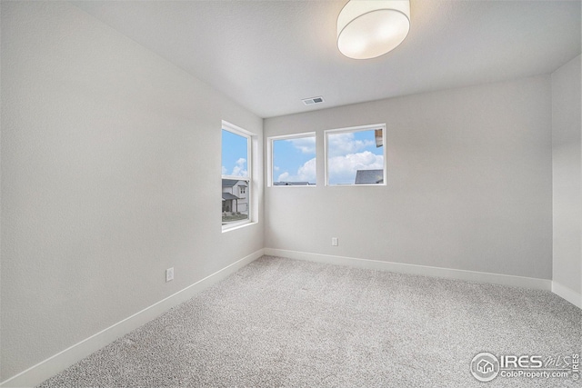 unfurnished room with baseboards, visible vents, and carpet