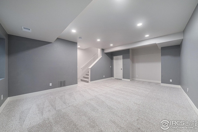 finished below grade area featuring stairway, visible vents, recessed lighting, and carpet flooring