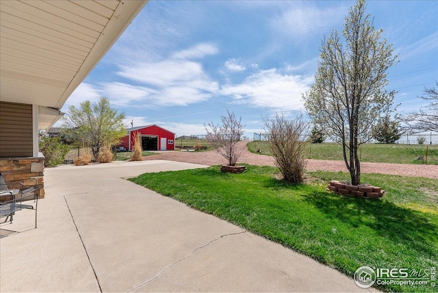 view of green lawn with an outdoor structure and driveway