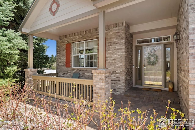 property entrance with a porch and brick siding