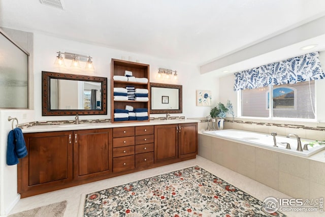 bathroom with double vanity, a bath, visible vents, and a sink