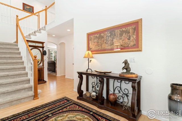 entryway featuring baseboards, wood finished floors, arched walkways, and stairway