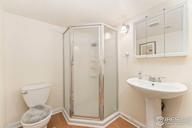 bathroom with a shower stall, wood finished floors, visible vents, and toilet