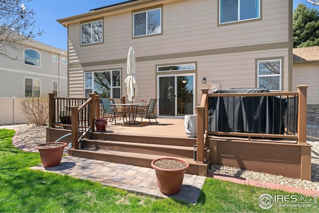rear view of property with fence, a wooden deck, and outdoor dining area