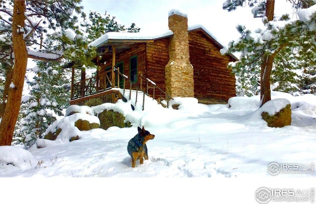 snow covered property with a chimney