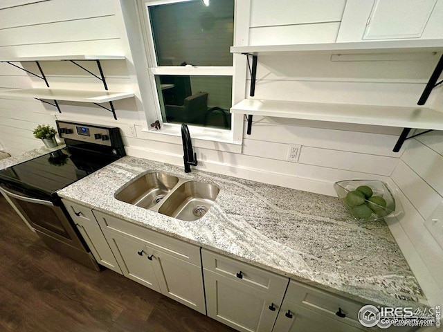 kitchen with a sink, light stone counters, stainless steel range with electric stovetop, open shelves, and dark wood-type flooring