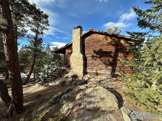 view of side of home featuring a chimney and stairway