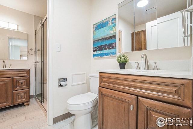 full bath featuring two vanities, toilet, a stall shower, and a sink