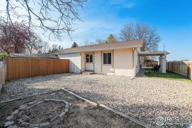 view of front facade featuring a fenced backyard, a front lawn, a patio area, an outdoor structure, and a storage unit