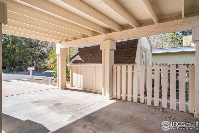 view of side of property with a storage shed, driveway, an attached carport, fence, and an outbuilding