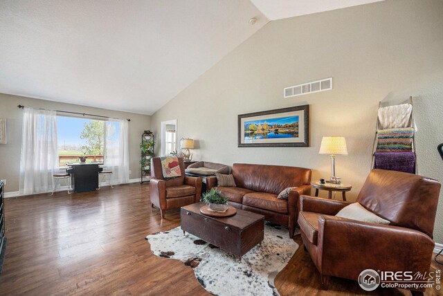living room featuring baseboards, wood finished floors, visible vents, and high vaulted ceiling