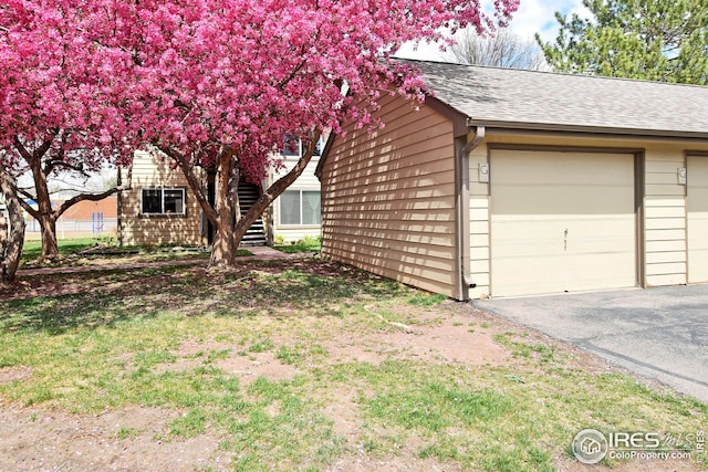 view of side of property with roof with shingles and a garage