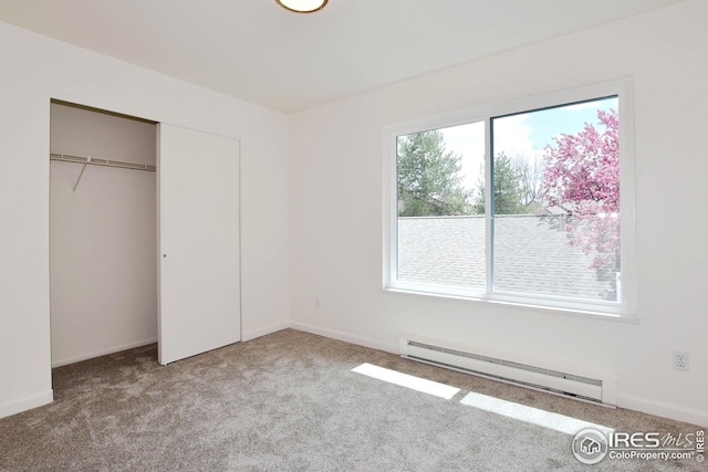 unfurnished bedroom with baseboard heating, baseboards, a closet, and carpet
