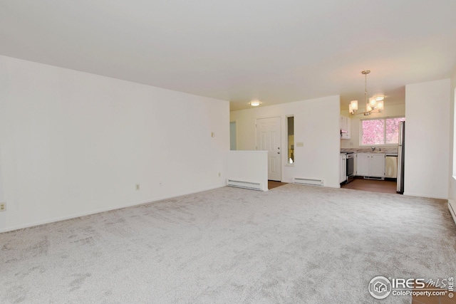 unfurnished living room featuring a baseboard heating unit, carpet flooring, a sink, and a chandelier