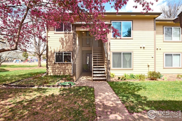 view of property featuring stairway and a front yard