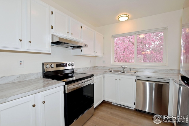 kitchen with white cabinets, stainless steel appliances, under cabinet range hood, and a sink