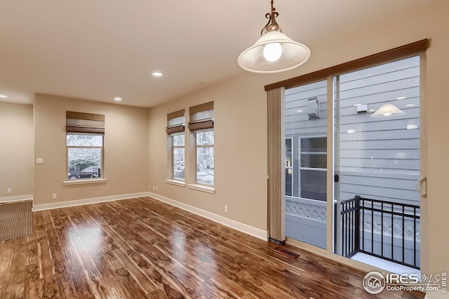 unfurnished dining area featuring baseboards, wood finished floors, and recessed lighting