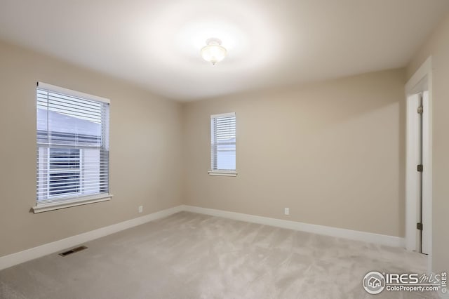 empty room featuring baseboards, visible vents, and light colored carpet