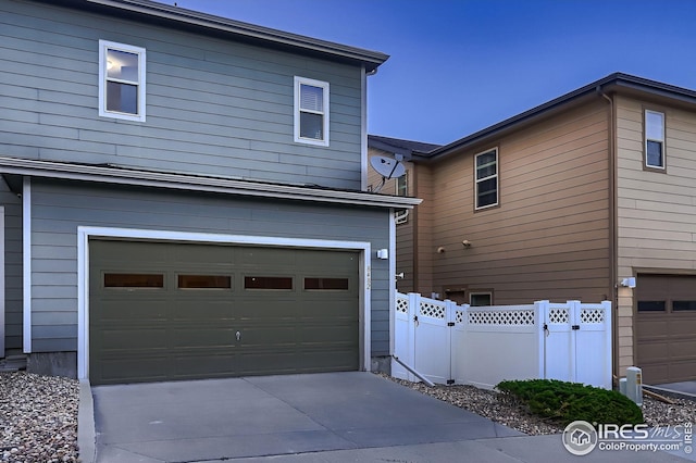 view of property exterior featuring a garage, concrete driveway, and fence