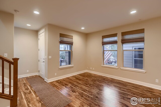 empty room featuring baseboards, stairs, wood finished floors, and recessed lighting