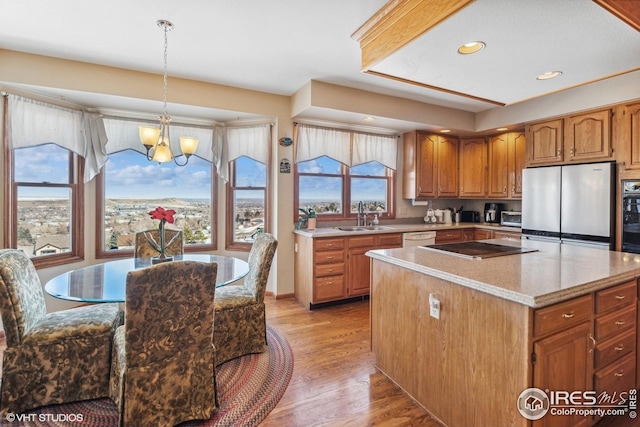 16261 W Ellsworth Ave, Golden, CO 80401 - kitchen with black appliances, a sink, a chandelier, light wood finished floors, and a kitchen island