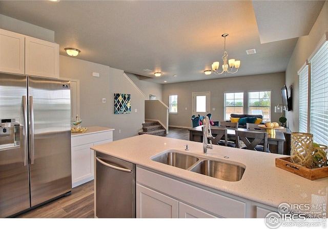 kitchen with white cabinets, a sink, light wood-type flooring, appliances with stainless steel finishes, and open floor plan