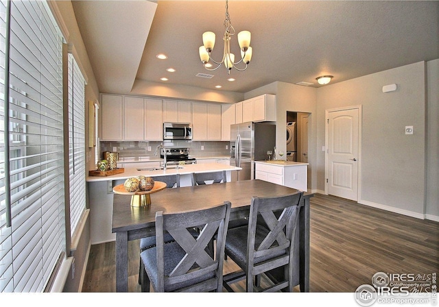 kitchen with white cabinets, backsplash, a notable chandelier, light countertops, and appliances with stainless steel finishes